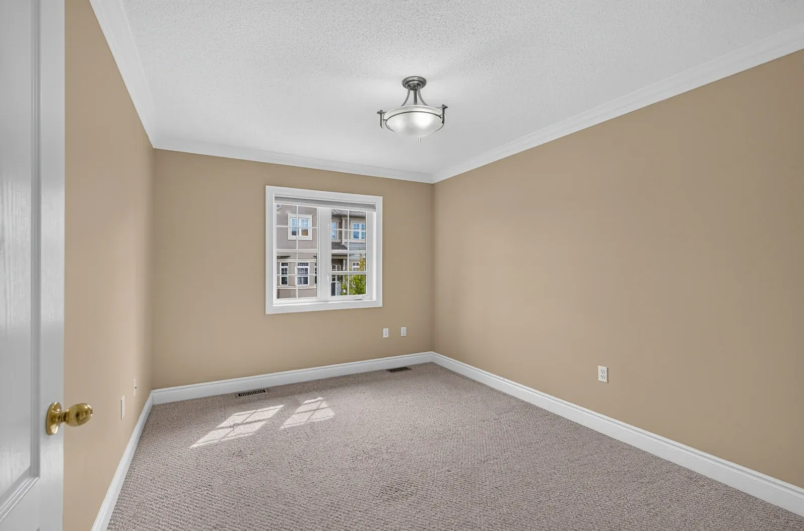 Empty kids' room with beige walls, carpet and a window, before virtual staging