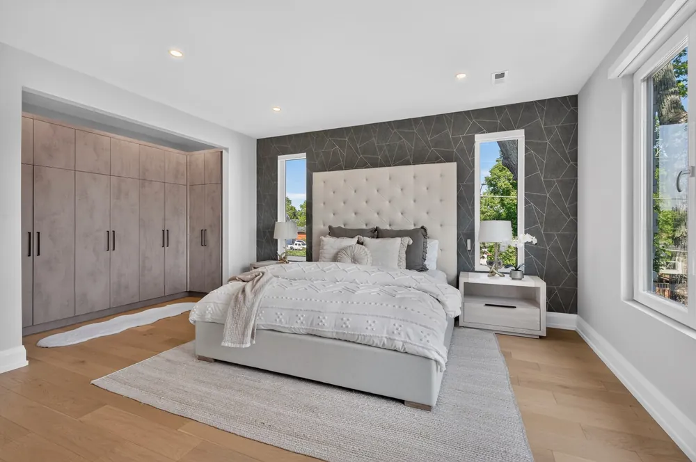 Primary bedroom with a tall tufted headboard, geometric feature wall and built-in wardrobes